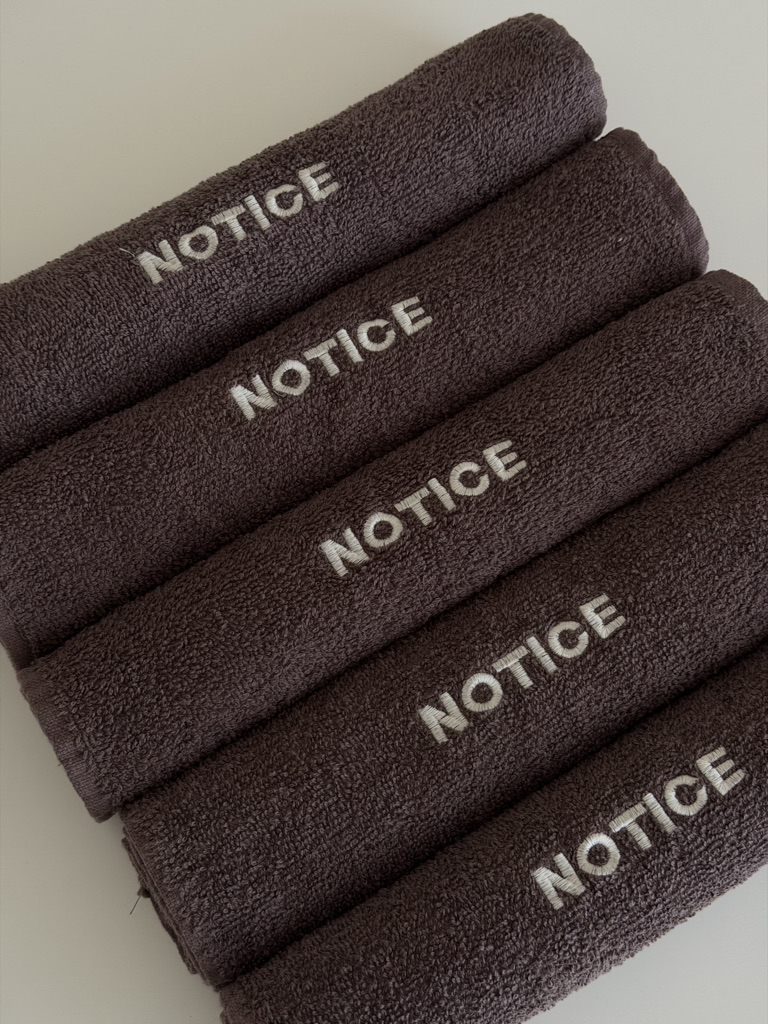 Taupe NOTICE towels with embroidered logos
